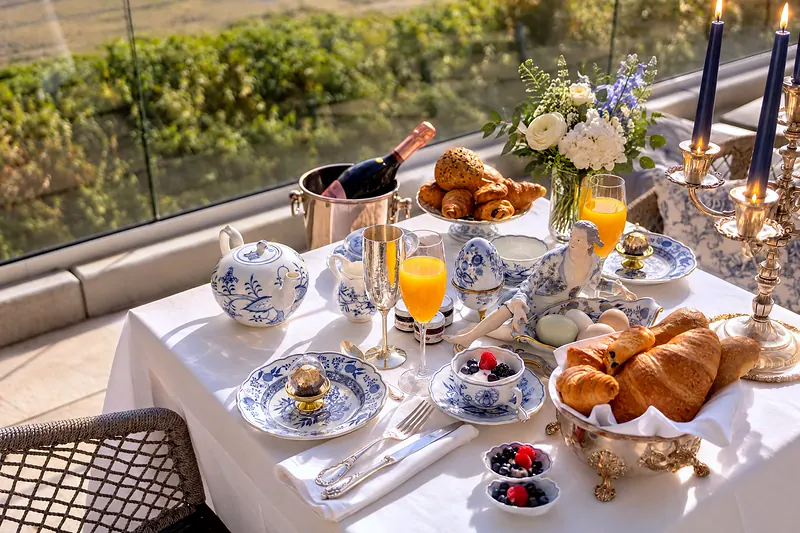 Ein gedeckter Frühstückstisch auf der Terrasse, dahinter die Wiesen