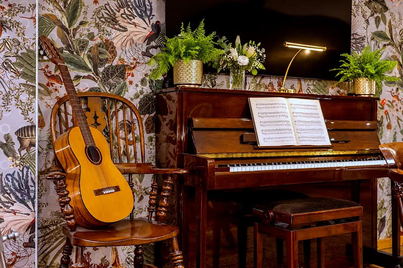 Ein Klavier mit aufgeschlagenen Noten, daneben eine Gitarre