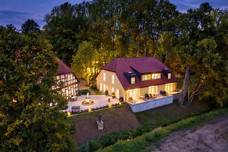 Der Landsitz am Abend von oben, alle Fenster erleuchtet