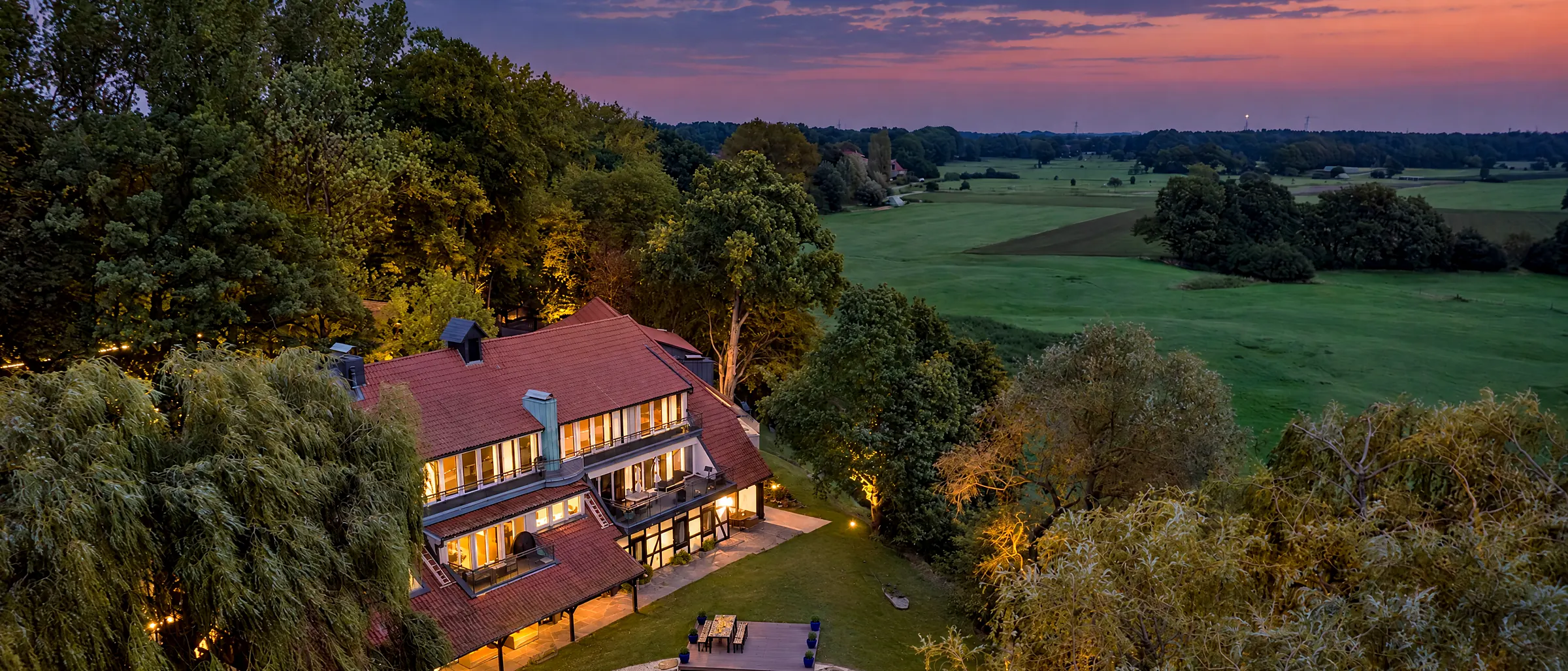 Luchtfoto van de Schlossresidenz in haar park, weilanden en vijver in avondlicht