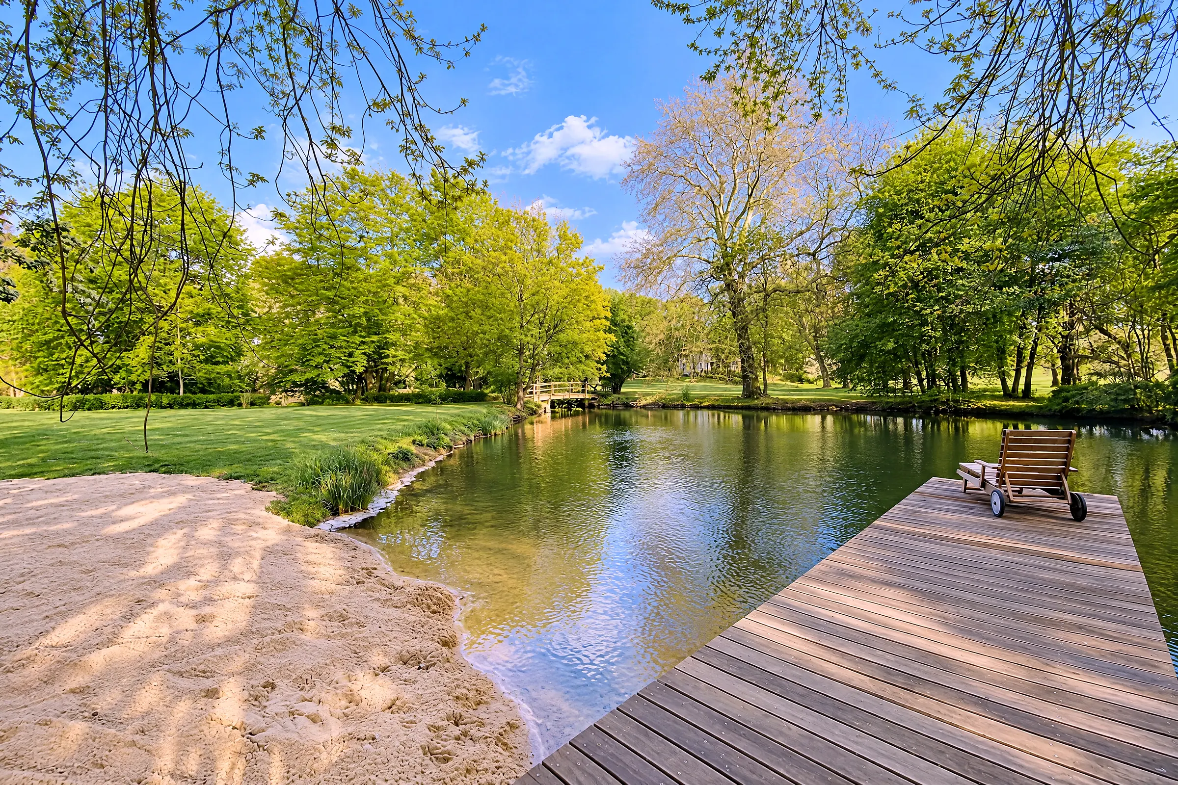 Het houten vlonder aan de zwemvijver, daarachter het park